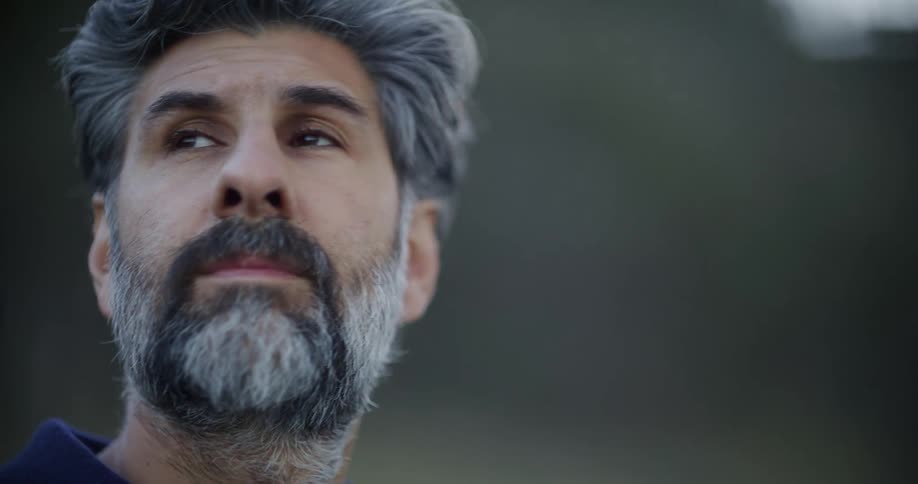 A serene and contemplative middle-aged man with a salt and pepper beard gazes upward in a moment of reflection