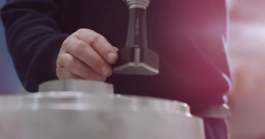 A man is lifting a tool over to a plate