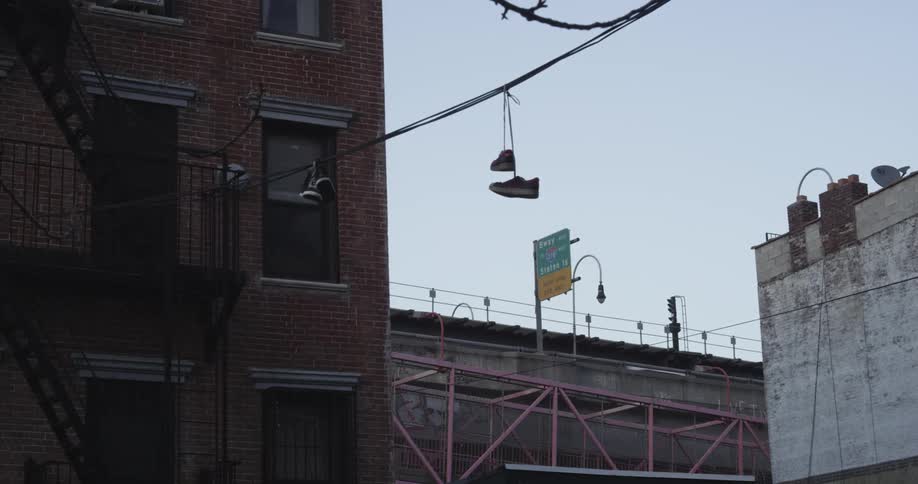 Pair of sneakers hangs from a power line attached to a building