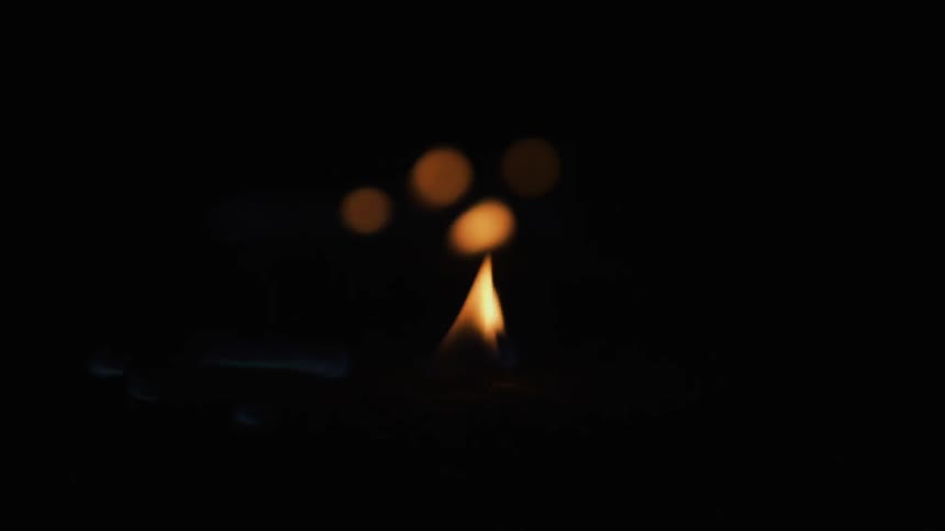 A flame flickers in the pitch black area