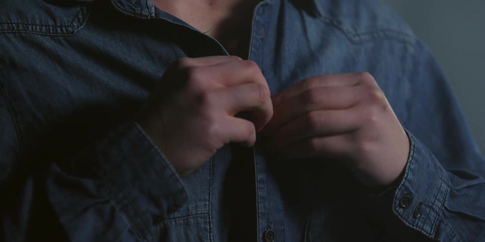 A man buttons his shirt