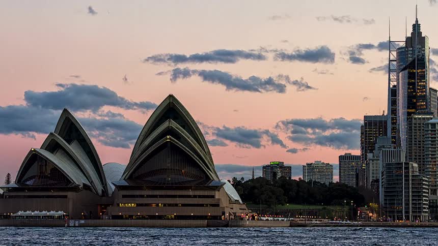 A stunning timelapse captures the transition from a beautiful sunset to night over the iconic Sydney Opera House and city skyline