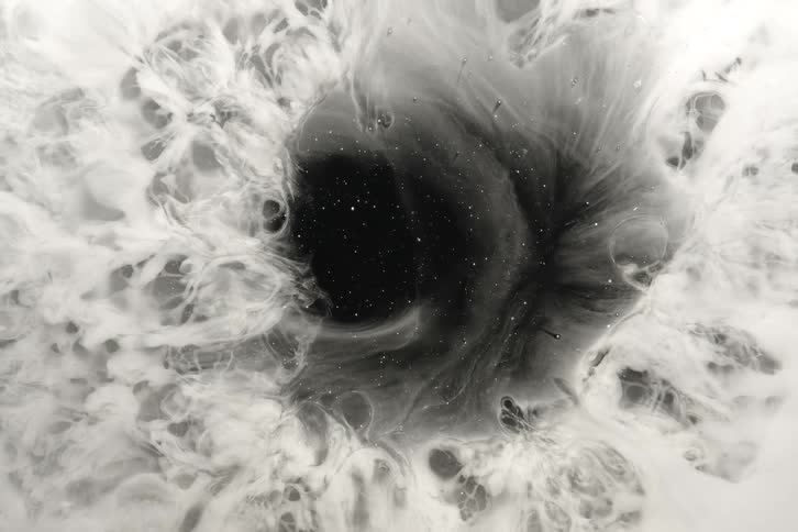 Monochromatic ink creates a mesmerizing cosmic swirl resembling a nebula around a dark, starry void
