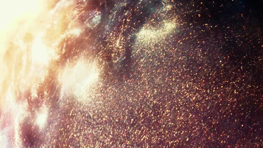 A brilliant light illuminates a cosmic swirl of shimmering golden glitter particles against a dark background