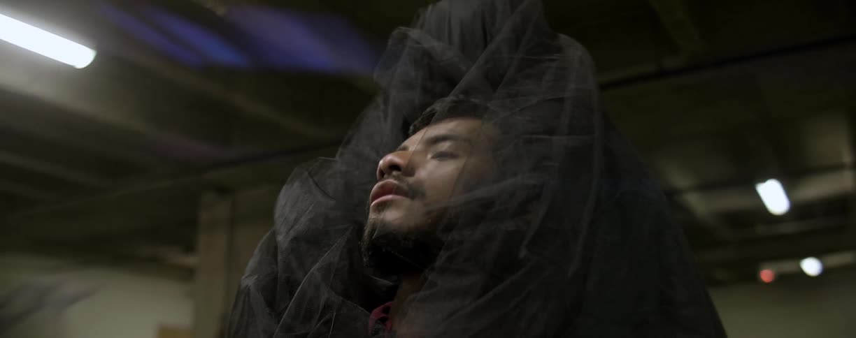 A man is being covered with black robes