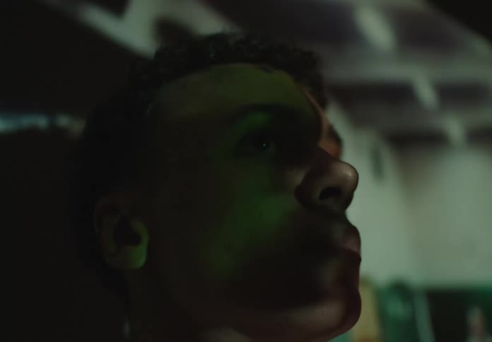 An artistic close-up of a young man's face as various images and lights are projected onto it