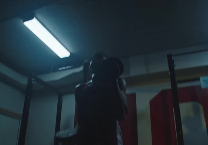Focused athlete performs intense bicep curls with heavy dumbbells in a dark, gritty gym