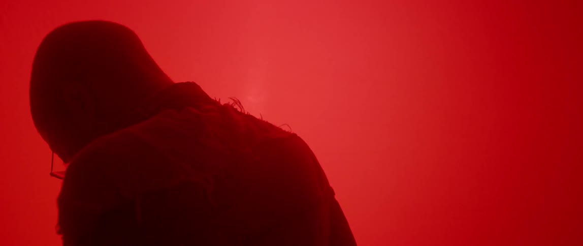 A person stands still in a room filled with red light