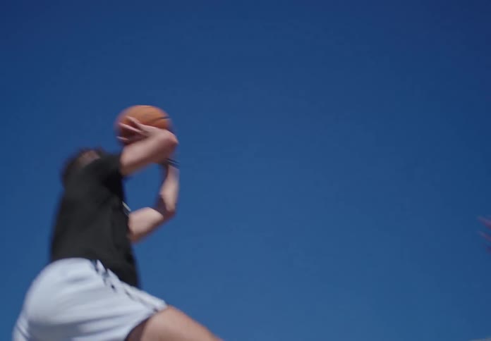 Dynamic shot captures two young men engaged in a competitive one-on-one basketball game on a sunny outdoor court