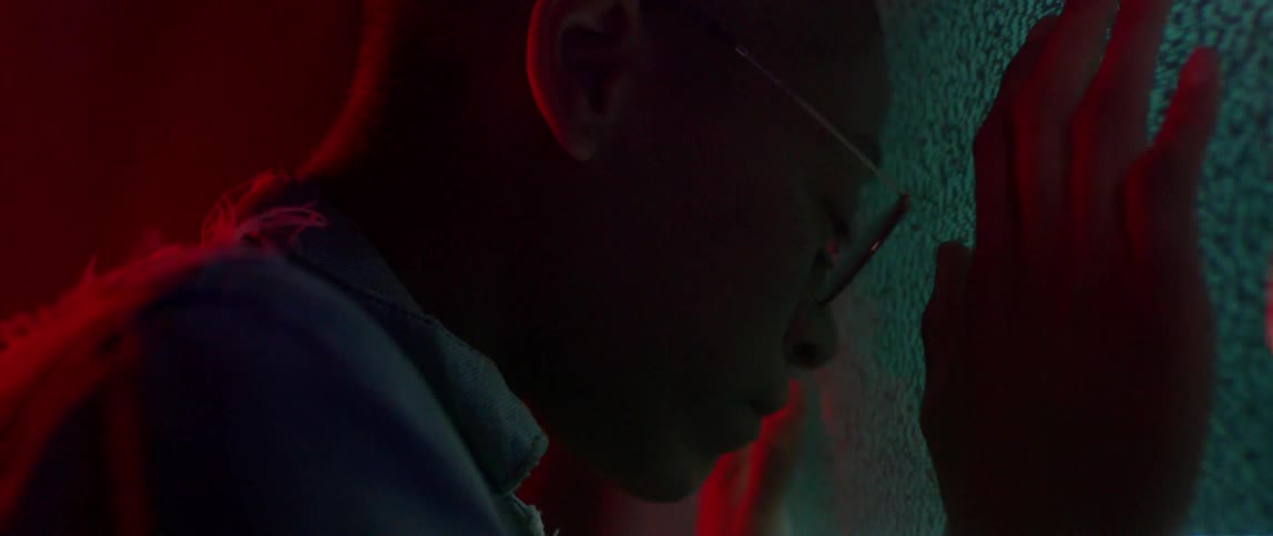 A person presses their head against a screen showing static