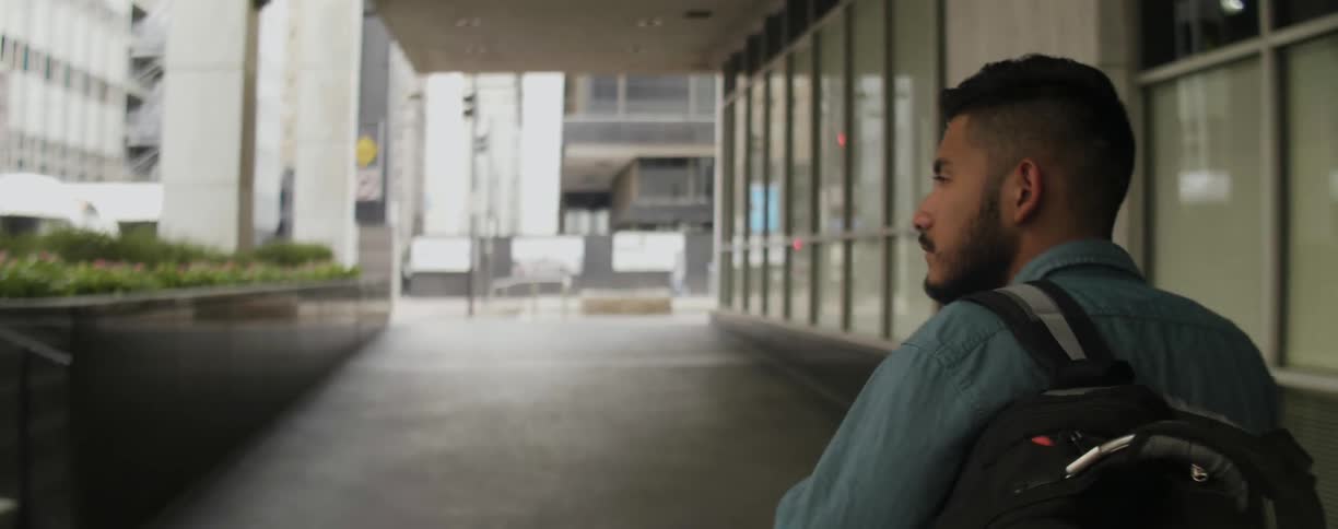 A man walks down the sidewalk looking at all the buildings
