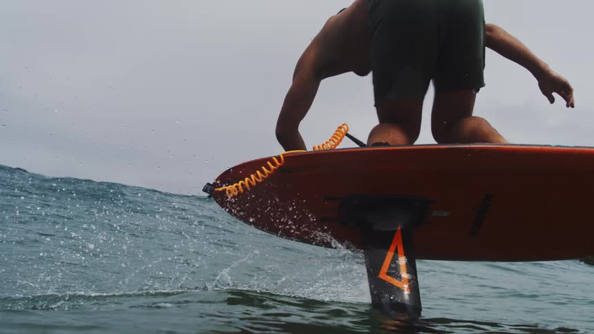 Slow motion shot of a skilled surfer gliding effortlessly over the ocean on a hydrofoil board