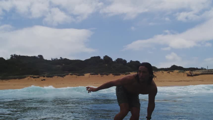 A man gracefully glides across the water on a hydrofoil surfboard in a dynamic slow-motion shot that ends with a splash