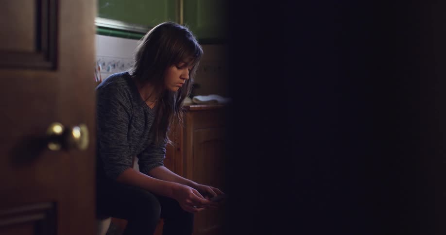 A woman sits in a bathroom
