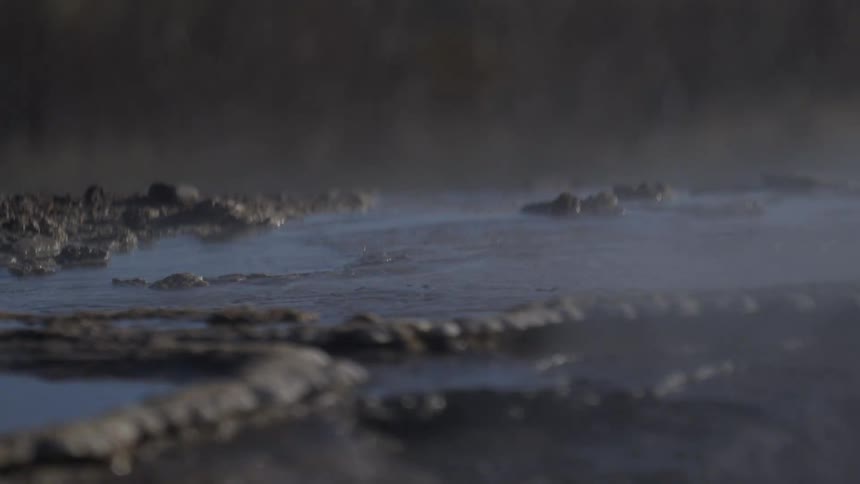 Close-up of a mysterious, steamy hot spring gently bubbling in slow motion