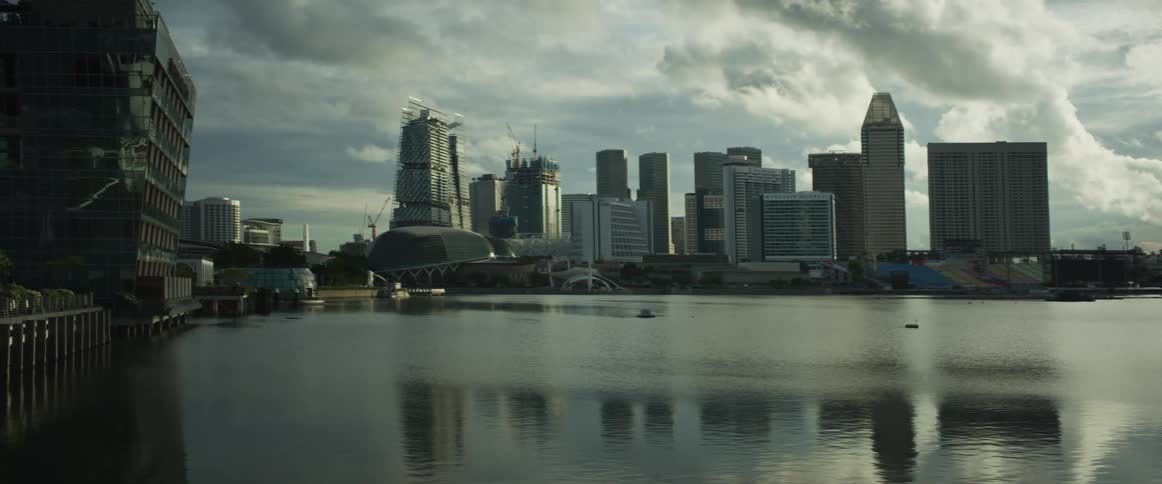 The modern city skyline of Singapore stands across the bay under a dramatic, cloudy sky