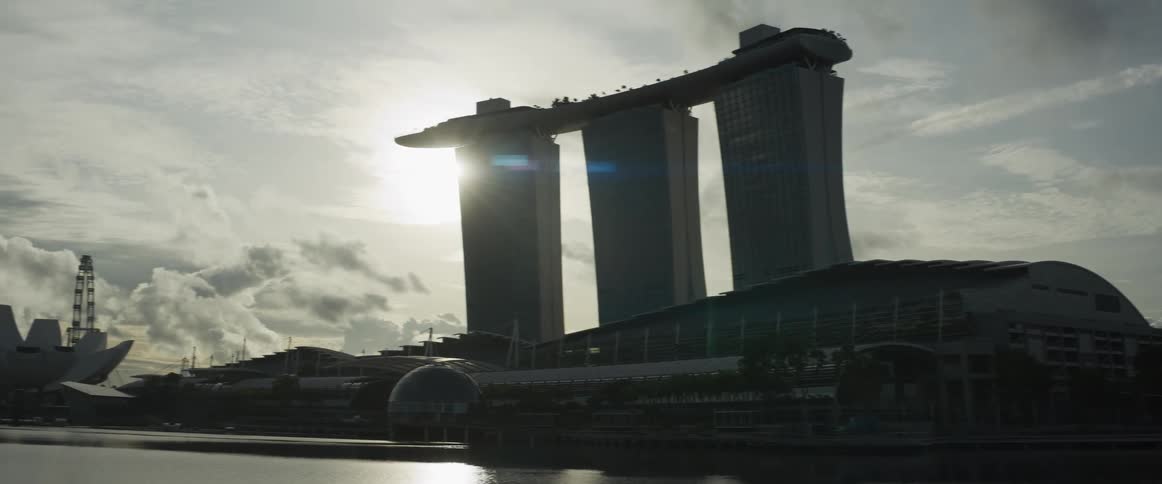 A slow pan across the Singapore skyline reveals the iconic Marina Bay Sands hotel and ArtScience Museum silhouetted against the morning sun over the water