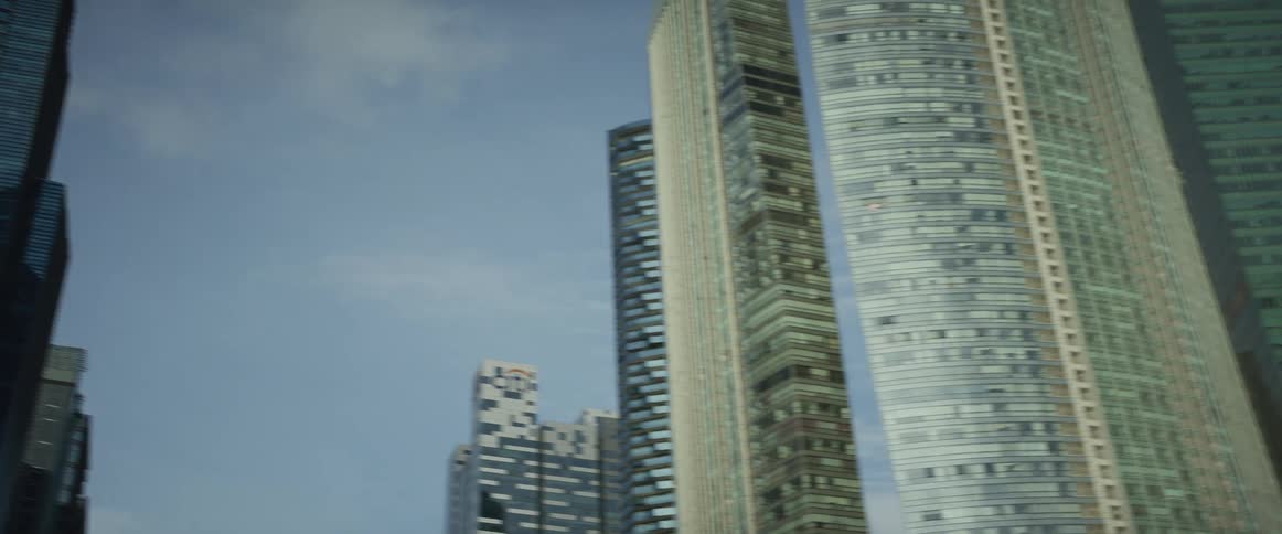 A slow pan shot looking up at the modern glass skyscrapers of a downtown financial district