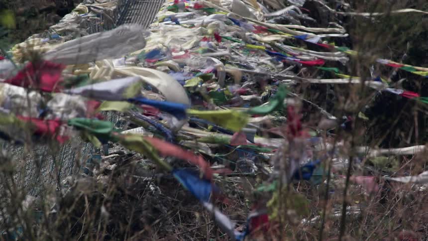 Flags and pieces of fabric attached to a bridge blow in the wind