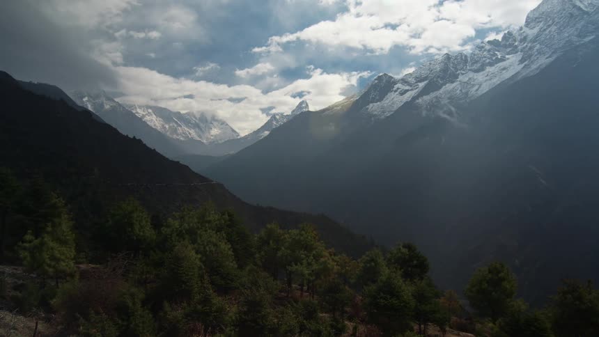 The mountains are high and covered with snow and clouds