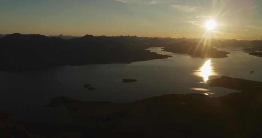 A breathtaking aerial perspective captures the serene beauty of a sunset over silhouetted mountains and tranquil waters