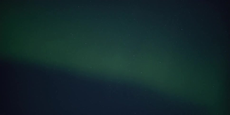 A faint green aurora borealis gently drifts across the vast, star-studded cosmos