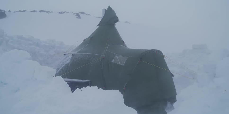 A survival tent stands strong against the fierce winds and heavy snowfall of a powerful arctic blizzard