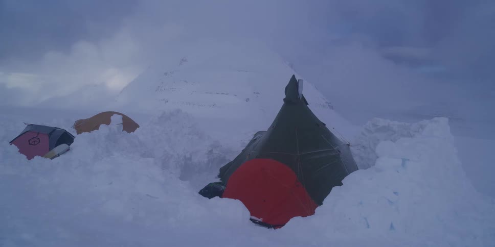 An expedition campsite with tents is battered by a fierce blizzard in a desolate, snow-covered mountain landscape