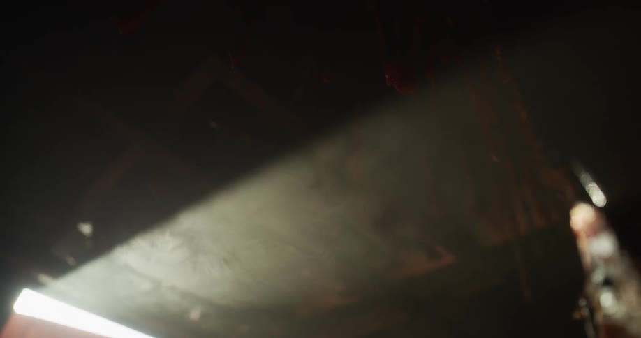 Mysterious smoke swirls through a bright sunbeam in a dark, atmospheric room