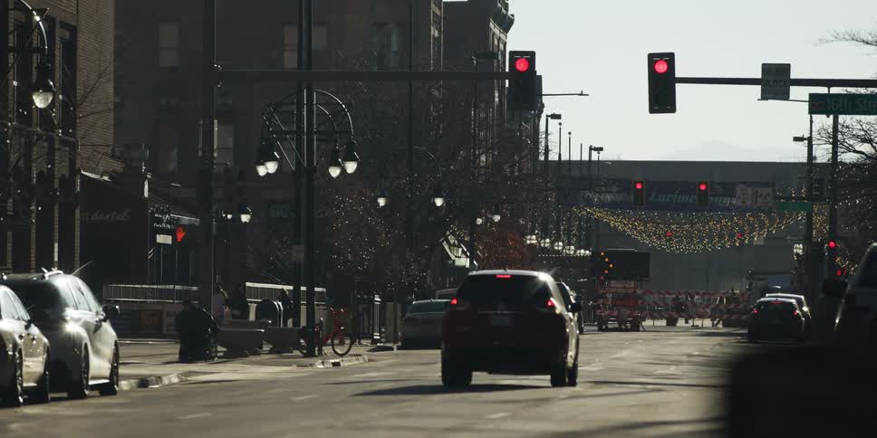 A long lens view of cars stopped at a red light on a downtown city street on a sunny day