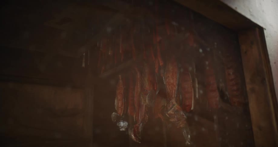Swirling smoke cures salmon fillets hanging to dry in a rustic smokehouse