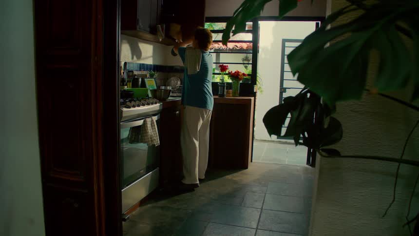 A man happily prepares a meal in his cozy kitchen, dancing as he leaves the room