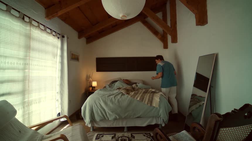 A loving man brings his partner a surprise pancake breakfast in bed in their cozy, rustic bedroom