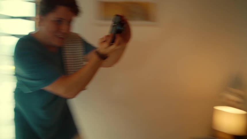 A playful man surprises his girlfriend with breakfast in bed and takes candid photos of her as she laughs and enjoys her pancakes