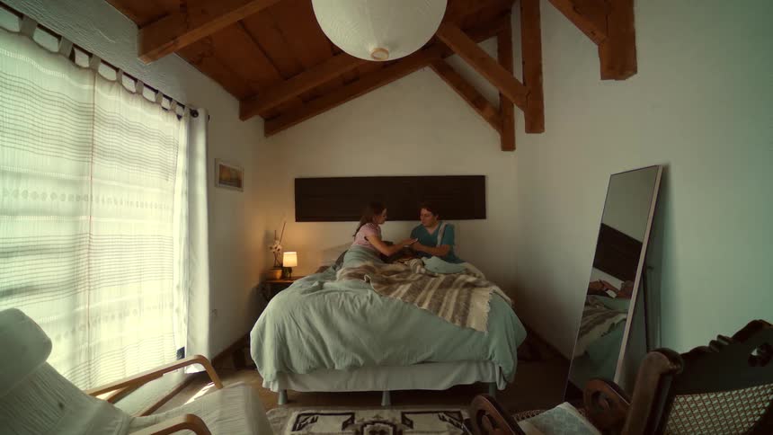 A caring man surprises his sleeping partner with a romantic breakfast of pancakes in bed in their cozy, rustic-style bedroom