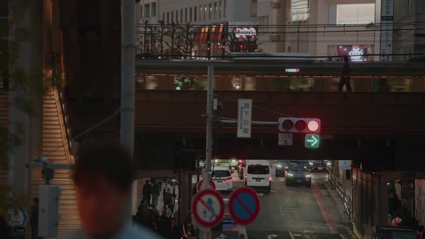 A dynamic Tokyo street scene at dusk shows pedestrians on an overpass while a train speeds by on an elevated track above the city traffic below