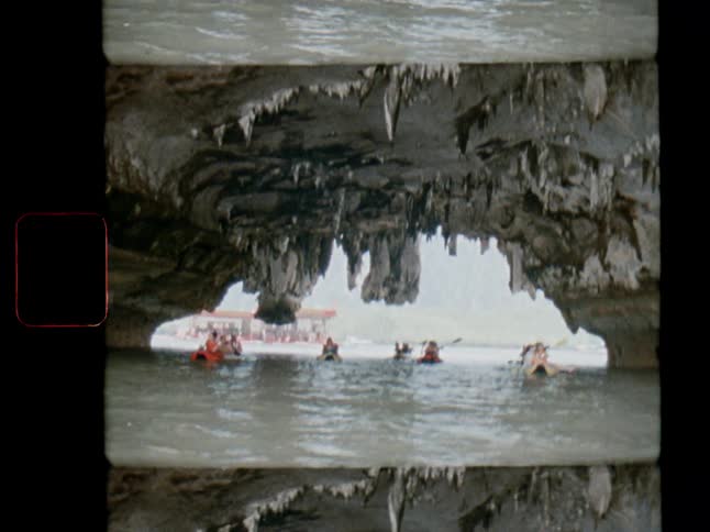 Vintage 8mm film captures tourists exploring a beautiful sea cave with stalactites in their kayaks