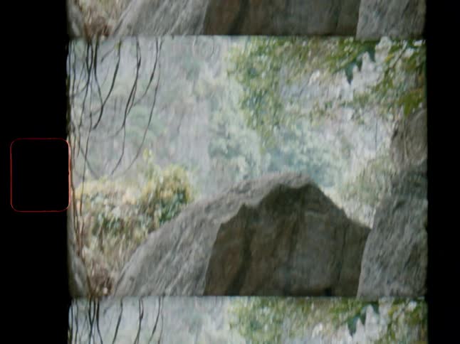 A split-screen Super 8 film effect shows a tilt down through a lush jungle to reveal large boulders