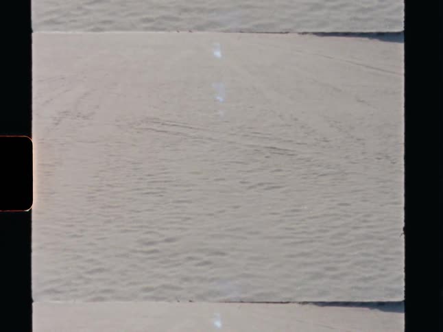 A static Super 8 film shot captures the minimalist texture of white sand dunes