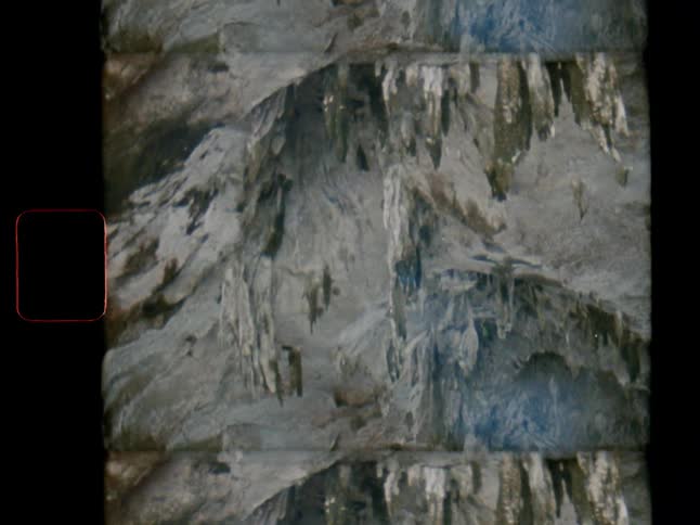 Vintage Super 8 footage shows the abstract, mirrored interior of a dark cave with stalactites and stalagmites
