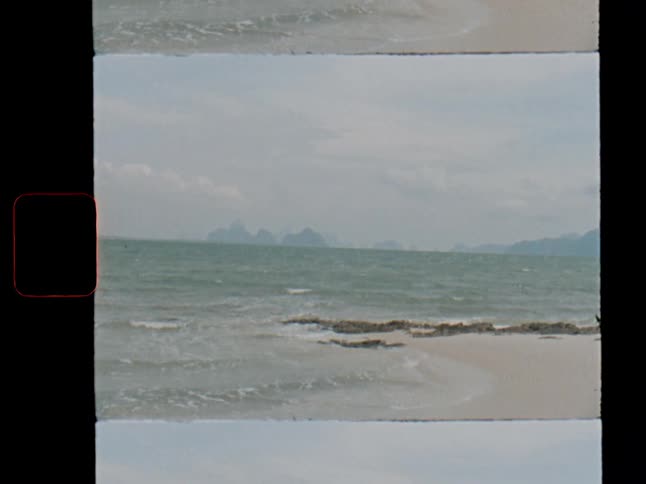 Nostalgic film scan of a serene tropical beach with gentle waves and islands on the horizon
