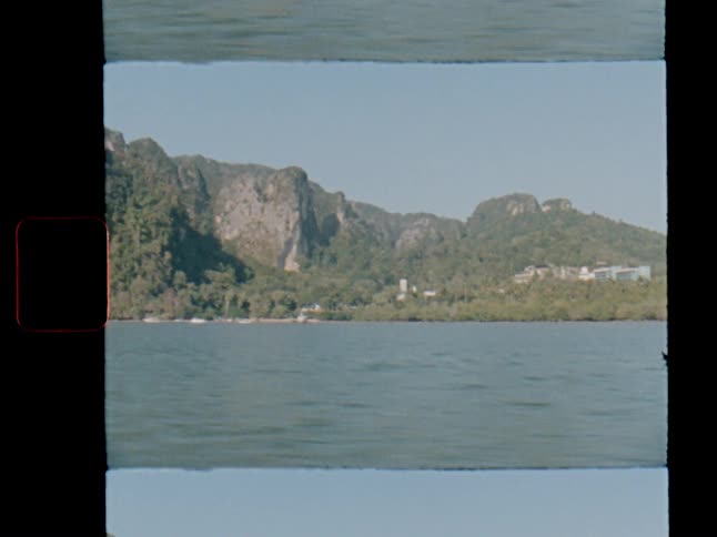 Vintage Super 8 film captures a tranquil boat ride past the lush, rocky coastline of a tropical island