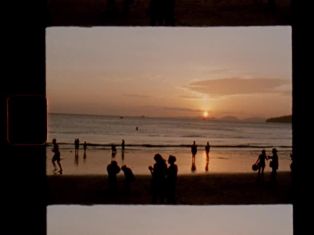 Silhouettes of people on a beach at sunset captured on a vintage film photograph