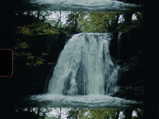 Surreal mirrored vintage Super 8 film footage shows a majestic waterfall cascading through a dense, dark forest
