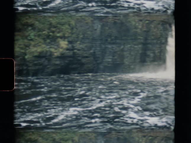 Vintage Super 8 footage shows a powerful waterfall cascading through a rocky gorge before panning to the rushing river below