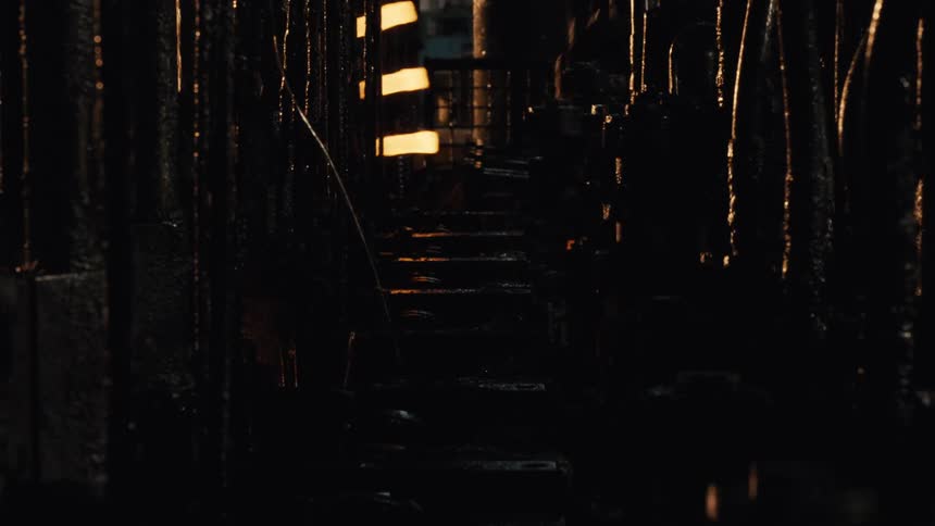 Close up of a stamping machine forging hot glowing metal parts in a dark industrial factory