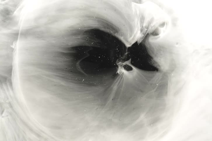 Ethereal white ink swirls and expands in slow motion around a dark, star-filled void