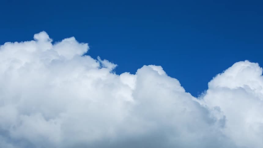 A serene time-lapse of fluffy white clouds drifting across a vibrant blue sky