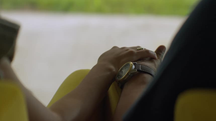 A romantic close-up of a woman's hand gently covering her partner's hand in a moving car