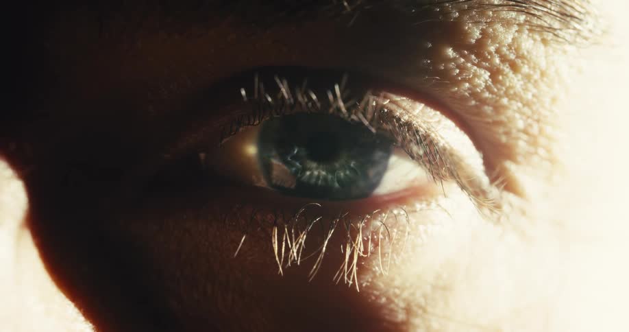 A dramatic macro shot of a person's eye slowly opening to the light